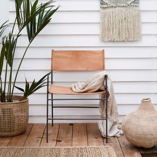 A room with white tongue-and-groove panelled wall, a wooden floor, a jute rug, sea grass baskets and a leather chair