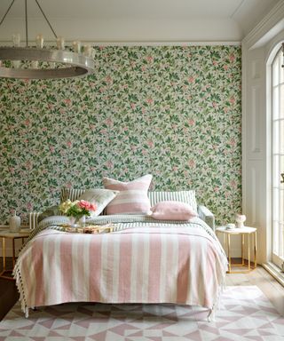 green and pink floral wallpaper in bedroom with pink patterned rug, throw and large chandelier light fitting