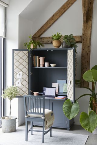 Small living room storage ideas featuring a dark grey cabinet opening into a desk with grey chair.