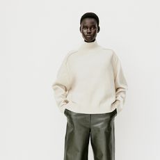 model wears white sweater and green wide leg pants 