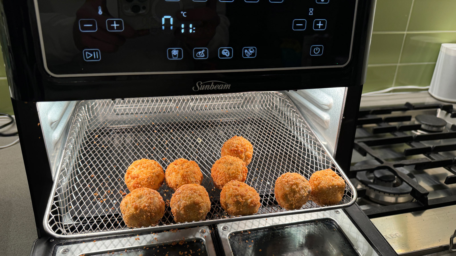 Uncooked arancini balls on an airflow tray, being inserted into the Sunbeam Multi Zone Air Fryer Oven