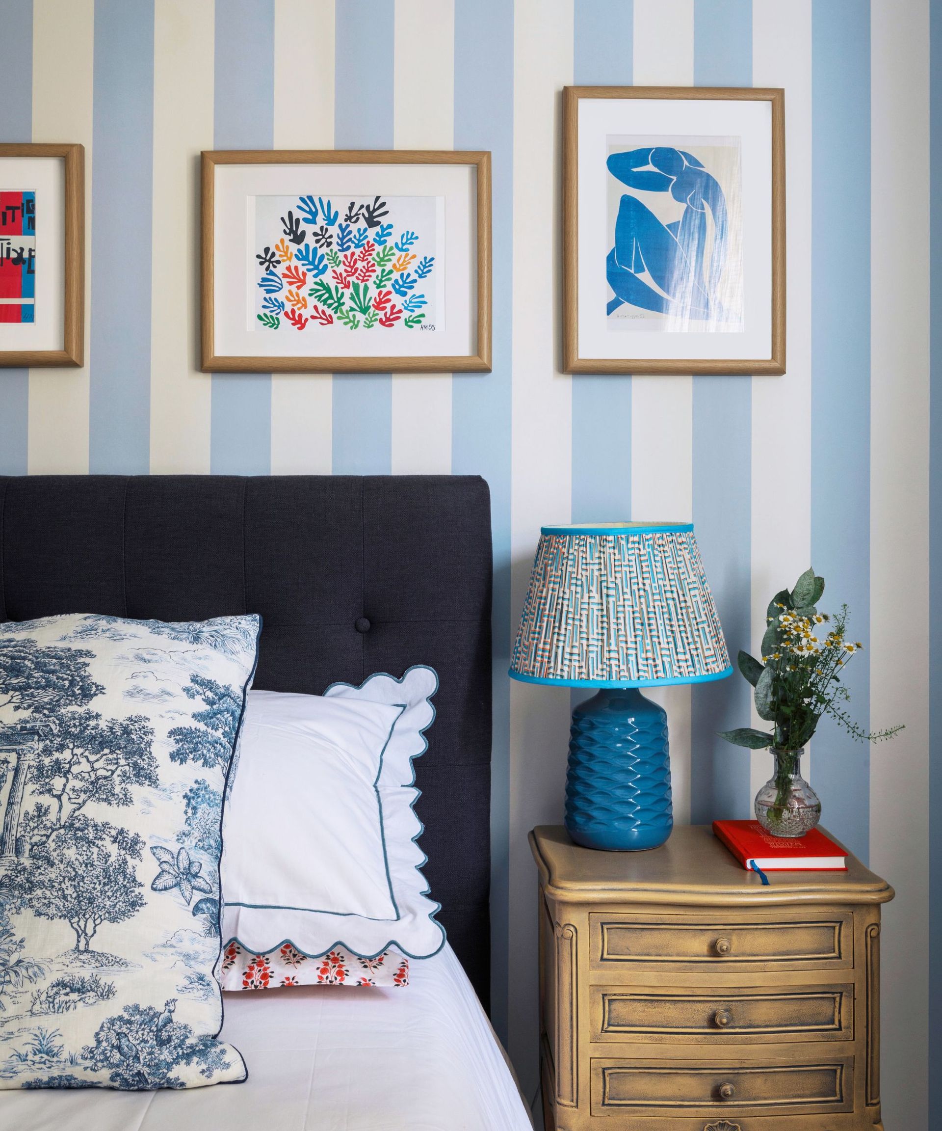 Bedroom with striped wallpaper and white bedding and pillowcases with scallop edging