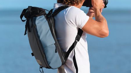 A photographer wearing the Wandrd Prvke Lite backpack in blue