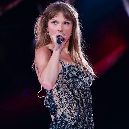 Taylor Swift sings onstage at the eras tour wearing a custom bodysuit