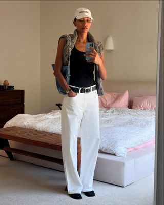 Woman wearing white jeans and a black tank top.