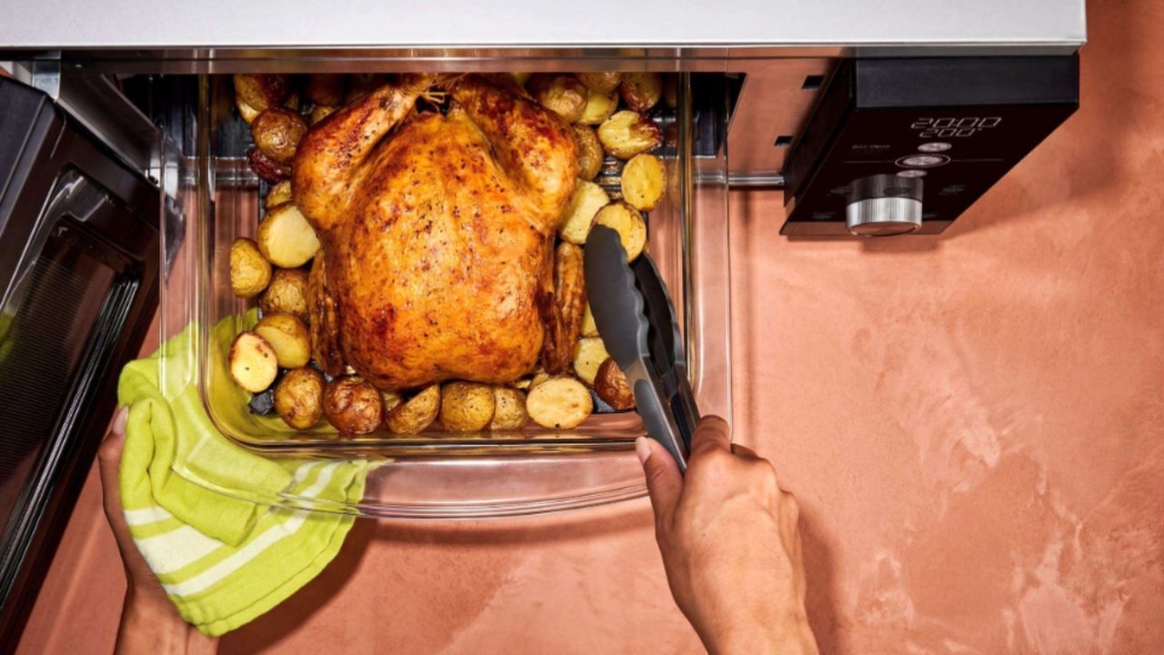 Ninja Crispi Microwave on a counter with a roast chicken which has been cooked inside it