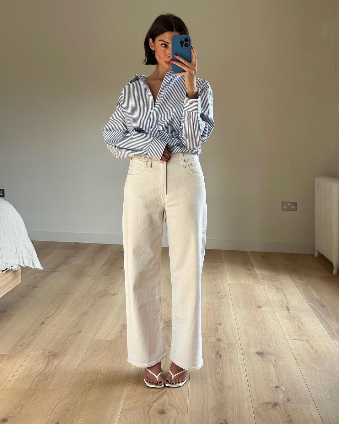 @smythsisters wears a blue striped shirt, white jeans and white heeled flip-flops
