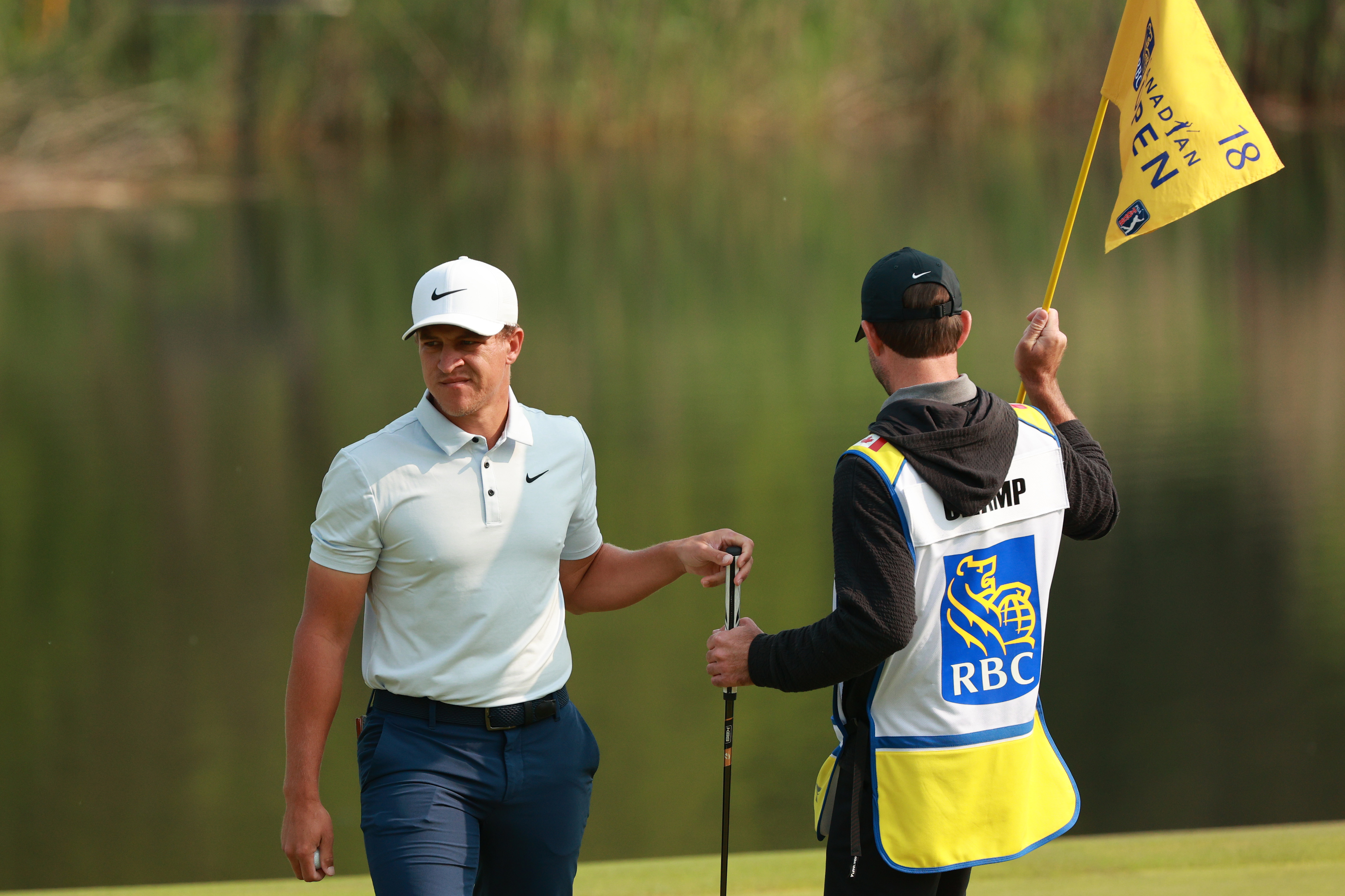 Cameron Champ hands his putter to his caddie