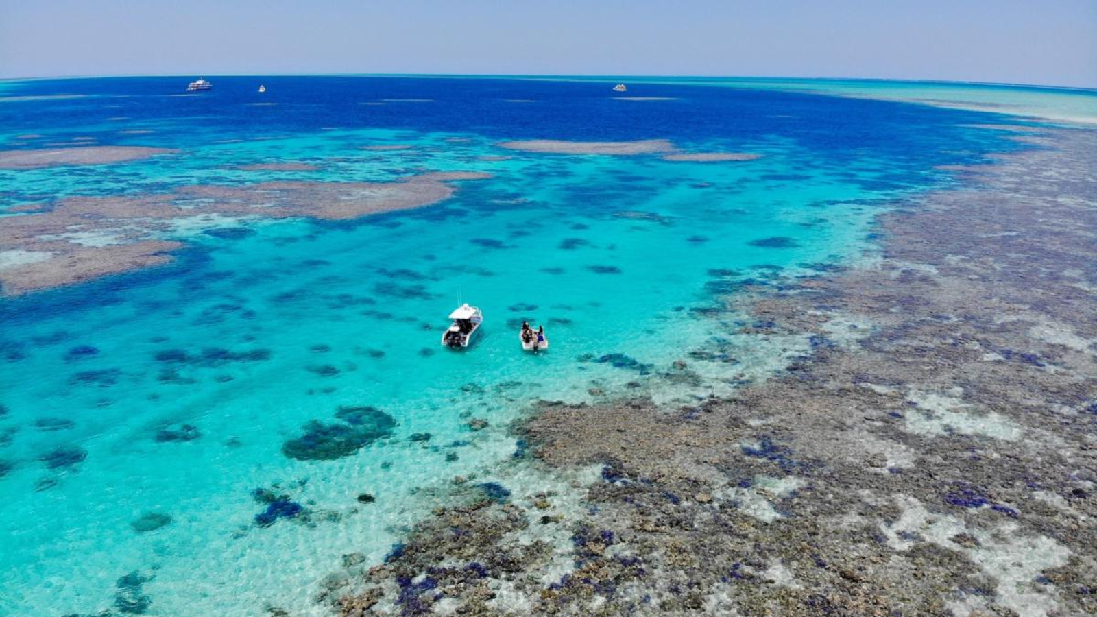 A photo of a boats sailing through the shallow waters of an atoll lagoon