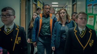 Bascombe and Frank walk with students in the school in Adolescence