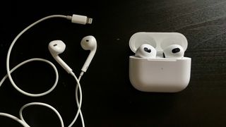 Apple AirPods 3 and EarPods with Lightning connection side by side on black background
