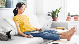 A woman uses one of the best USB-C mouse options while sitting on a sofa and using a laptop