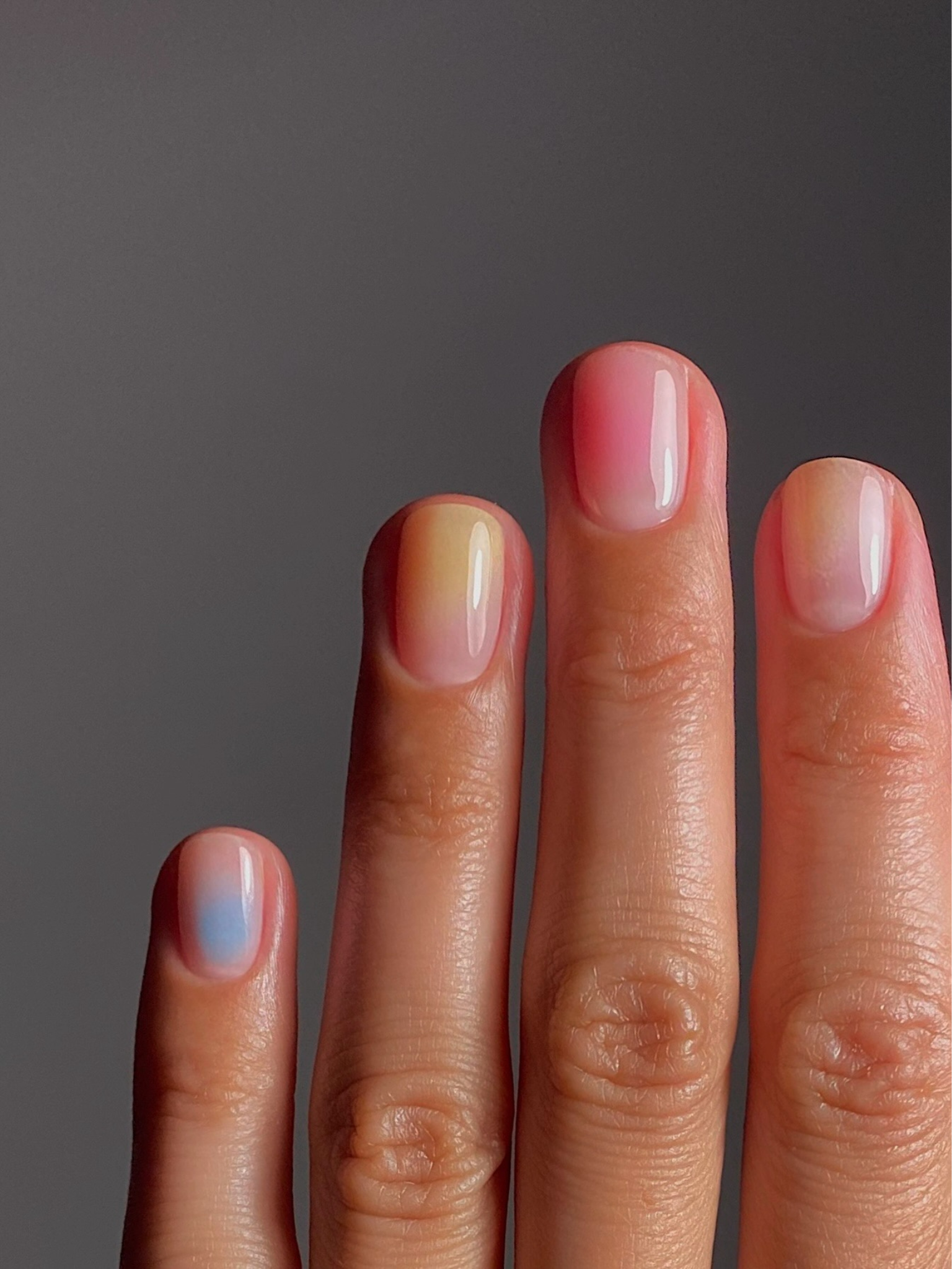 Subtle tie dye nails in a rainbow of colours across the hand.
