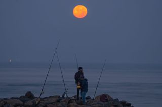 Fishermen catch a bite under the added illumination provided by the Wolf Moon in Colombo, Sri Lanka, on January 25, 2024