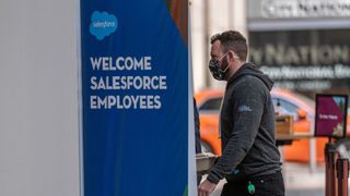 A man walking into a building next to a sign that says "Welcome Salesforce Employees"