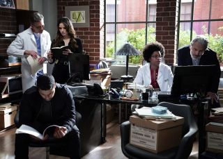 NCIS cast shot of characters in office reading though files