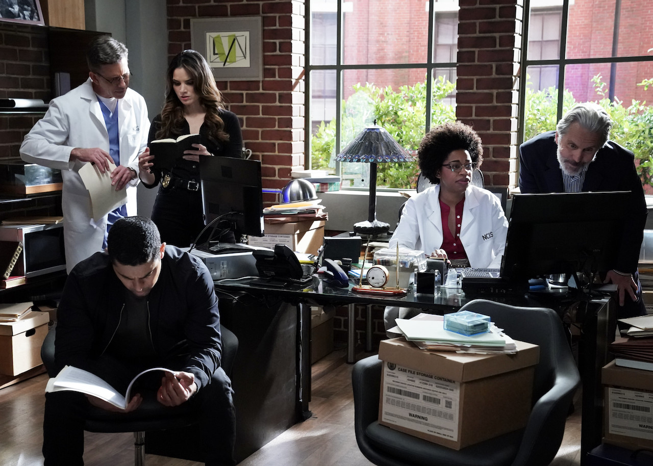 NCIS-Cast-Aufnahme von Charakteren im Büro, die Akten durchlesen