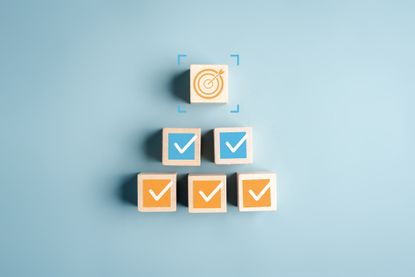 wooden block with a bullseye with two blocks with blue check marks and three blocks with orange checkmarks underneath