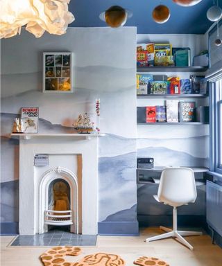 A blue kid's room with a small white fireplace and desk nook