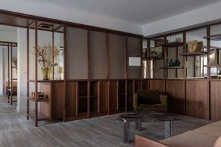 Green armchair in living room with walnut joinery.