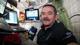 Canadian astronaut Chris Hadfield poses with his computer in the International Space Station on Jan. 11, 2013, He uses the computer to post updates and photos of his Expedition 34/35 mission on Twitter.