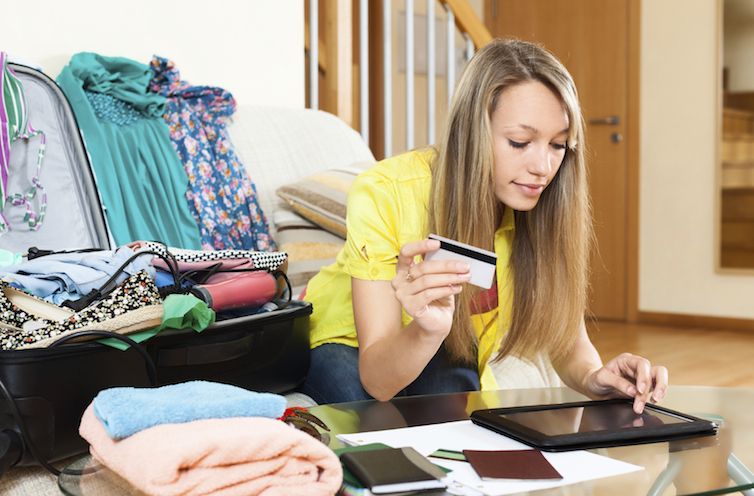 Young woman using credit card and tablet for reserving plane ticket online