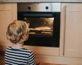 toddler child looking at oven while food cooks