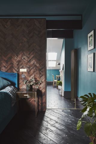 Lucy Kemp Victoria Road house: Dark bedroom with parquet wood-effect wall behind bed